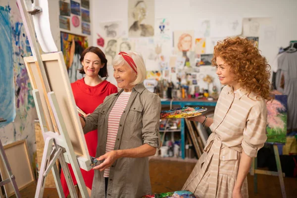 Studenten en kunst leraar glimlachen tijdens het schilderen en praten — Stockfoto