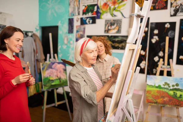 Aged art teacher drawing standing near her students — Stock Photo, Image