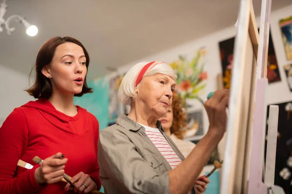 Estudante de cabelos escuros assistindo sua pintura de professor envelhecida — Fotografia de Stock