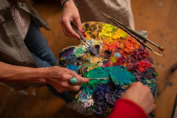 Konstnärer som håller sina borstar nära färgpalett — Stockfoto