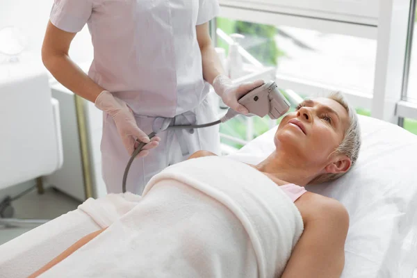 Serious aged woman having anti age facial treatment — Stock Photo, Image