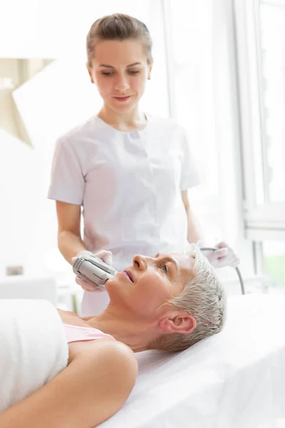 Bonito cosmetólogo experto mirando a su cara clientes — Foto de Stock