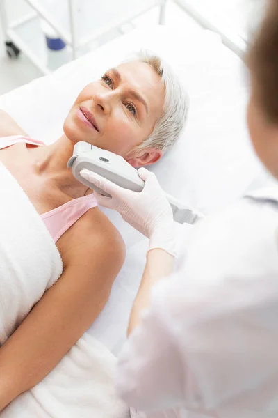 Positive grey haired woman enjoying her anti age procedure — Stock Photo, Image