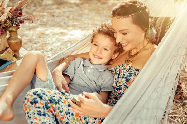 Feliz hermosa mujer acostada en hamaca con su hijo — Foto de Stock