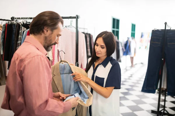 Aantrekkelijke donkerharige bebaarde man die de kwaliteit van een blazer controleert — Stockfoto