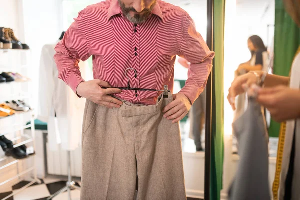 Close-up picture of adult attractive tall trying on beige trousers. — Stock Photo, Image