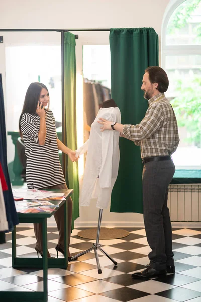 Handsome talented good-looking fashion designer tailoring a white shirt