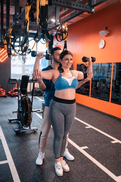 Obese woman wearing grey leggings working out near trainer