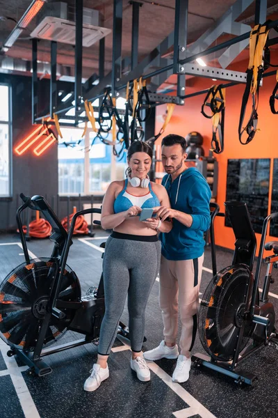 Sakallı fitness eğitmeni müşteri için iyi bir spor uygulaması tavsiye