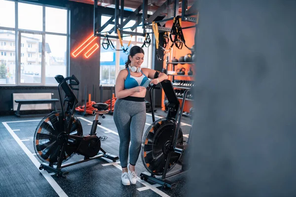 超重妇女穿着上衣使用她的手机在健身房 — 图库照片