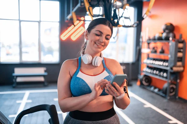 Mujer joven leyendo mensajes en el teléfono antes del entrenamiento — Foto de Stock