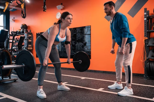 Overweight woman hardly breathing while lifting barbell
