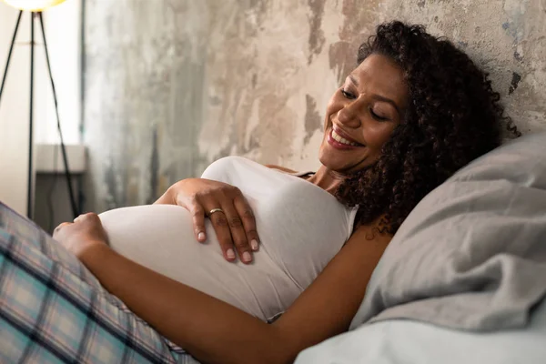 Schöne lächelnde Schwangere, die ihren Bauch berührt. — Stockfoto