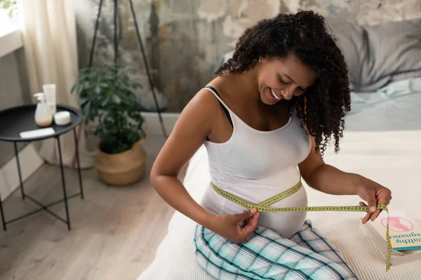 Mãe expectante medindo sua barriga no quarto . — Fotografia de Stock