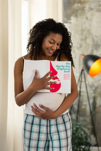 Zwangere vrouw houdt haar boek en haar buik. — Stockfoto