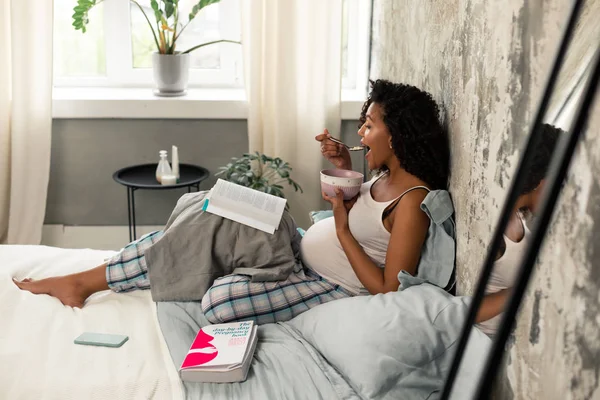 Zwangere vrouw die zichzelf omdoet met boeken. — Stockfoto