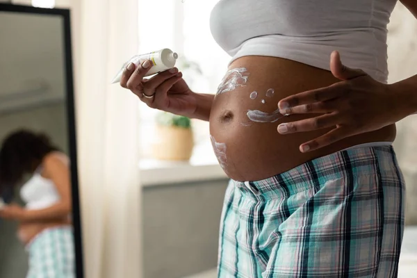 Handen van een zwangere vrouw haar buik afromen. — Stockfoto