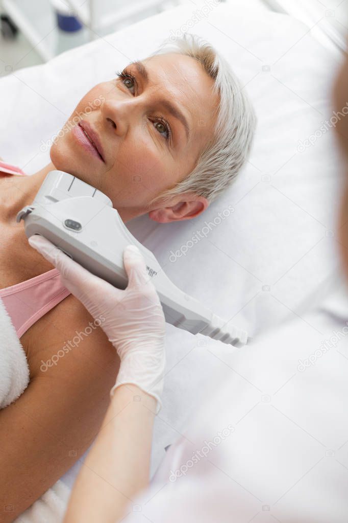 Nice aged woman having a microcurrent treatment procedure