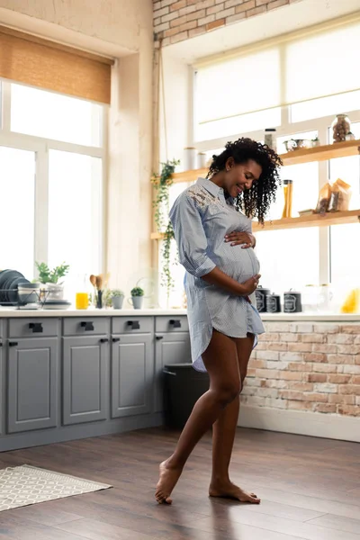 Zwangere dame houdt haar buik in de keuken. — Stockfoto