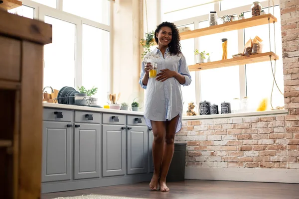 Беременная женщина с соком стоит на кухне . — стоковое фото