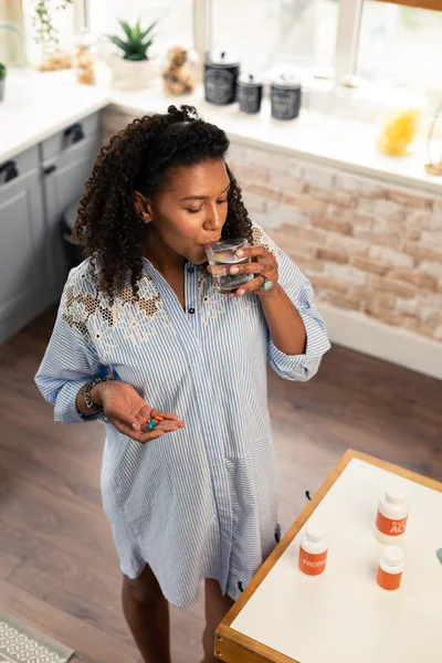 Expectant mother washing down her vitamins with water. — Stock Photo, Image