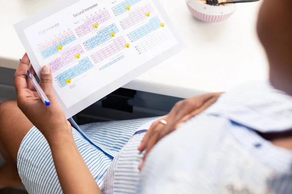 El calendario del embarazo en las manos de la mujer embarazada . — Foto de Stock