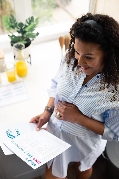 Zwangere vrouw glimlachend na het lezen van haar DNA-testrapport. — Stockfoto