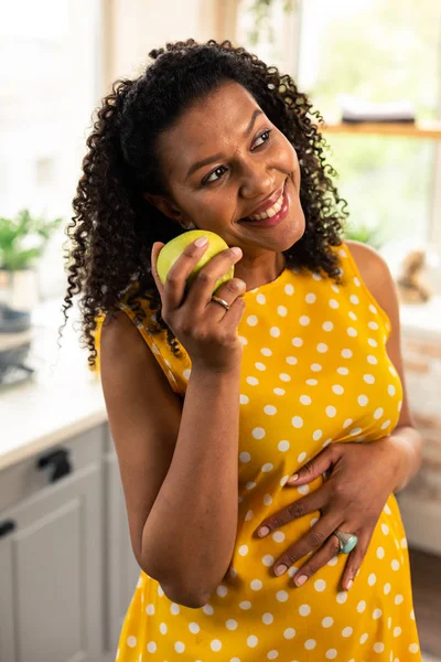 Беременная женщина держит яблоко и улыбается . — стоковое фото