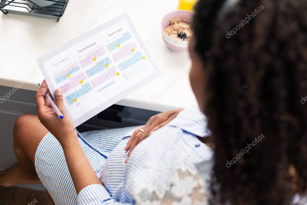 Pregnant woman attentively reading her pregnancy calender.