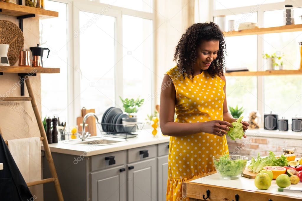 Pregnant woman chopping lettuce to make some salad.