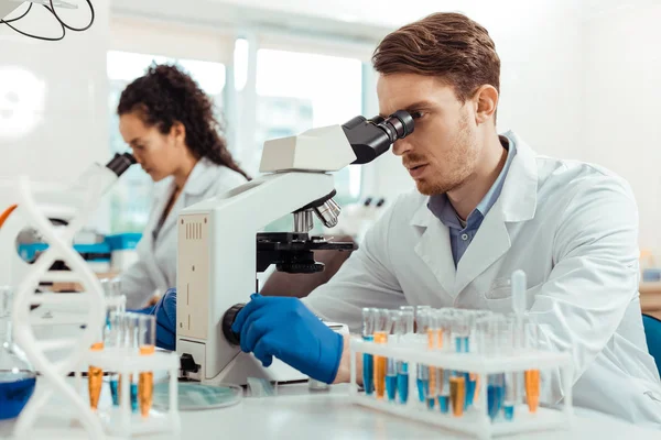 Jovem bonito olhando para o microscópio — Fotografia de Stock