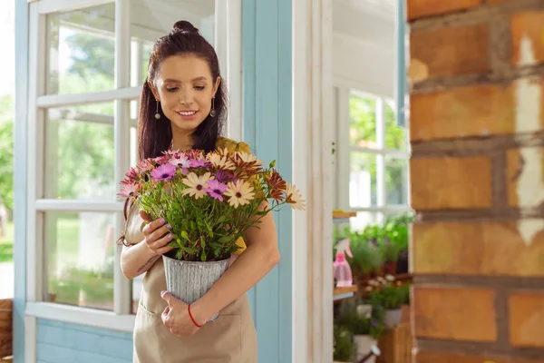 Schöne Frau hält einen Blumentopf auf der Veranda. — Stockfoto