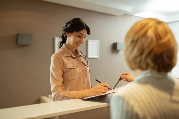 Frau lächelt beim Ausfüllen von Kontaktdaten in Schönheitsklinik — Stockfoto