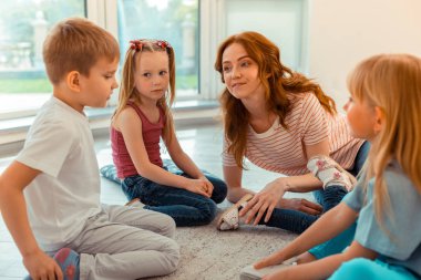 Güzel sevimli çocuklar öğretmen yanında oturan