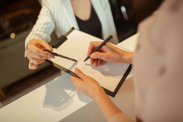 Donna che tiene la penna mentre scrive i dettagli personali in clinica — Foto Stock