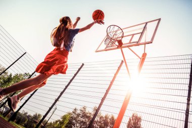 Uzun saçlı güzel kız bir basketbol oyun alanında spor yapıyor