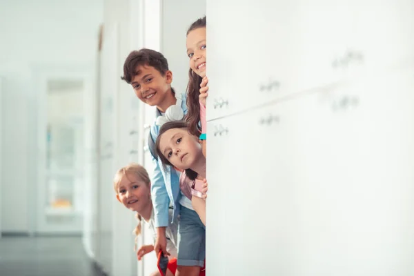 Garçon et les filles souriant tout en se tenant près des casiers à la pause scolaire — Photo