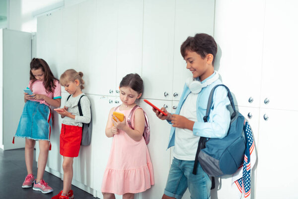 Children standing near lockers and playing video games