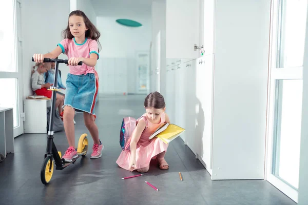 Chica morena montando scooter en el pasillo de la escuela — Foto de Stock