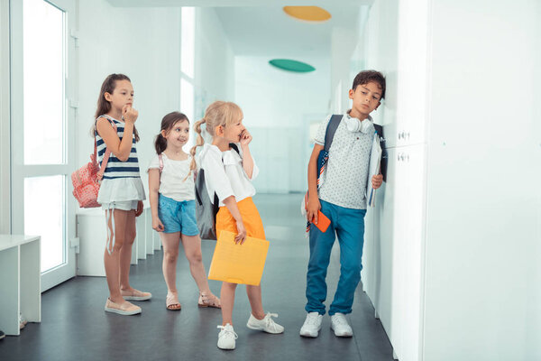 Rude schoolgirls laughing at boy feeling sad and lonely
