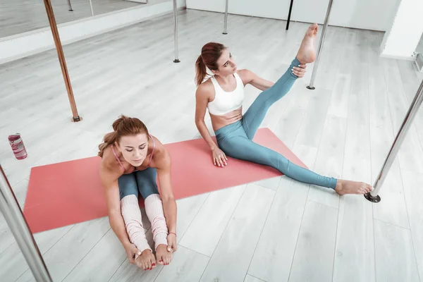 Zwei Frauen, die sich zusammen auf einer Matte strecken. — Stockfoto