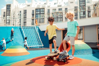 İki arkadaş birlikte bir spor sahasında kaykay.