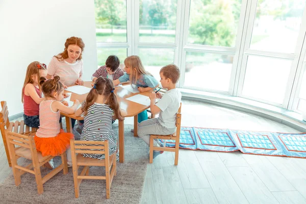 Nice creative kids sitting around the round table — Stock Photo, Image