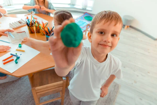Radosny szczęśliwy chłopiec pokazując kawałek plastiku — Zdjęcie stockowe