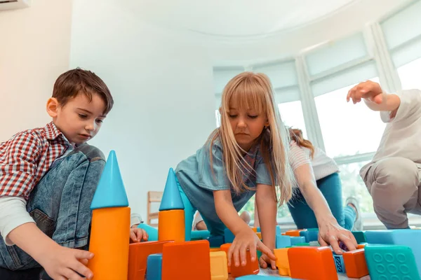 Alegre agradable niños construyendo una torre de juguetes — Foto de Stock