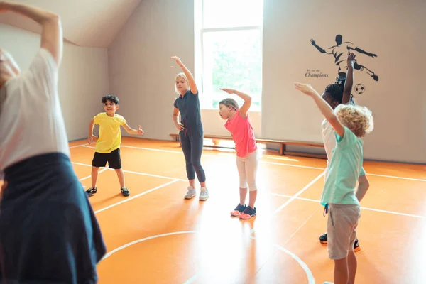 Elèves regardant leur entraîneur et essayant de répéter des exercices . — Photo