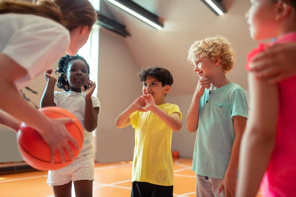 Kinderen glimlachen om hun sportleraar in de sportschool. — Stockfoto