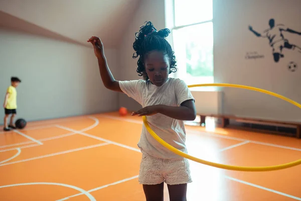 Estudante exercitando-se com hula hoop na aula de esportes . — Fotografia de Stock