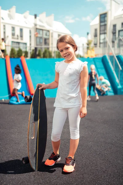 Sorrindo menina de pé com seu skate fora . — Fotografia de Stock