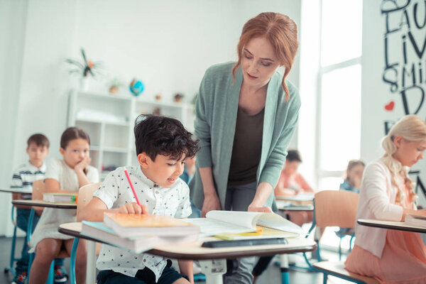 Pupil reading his homework to the teacher.